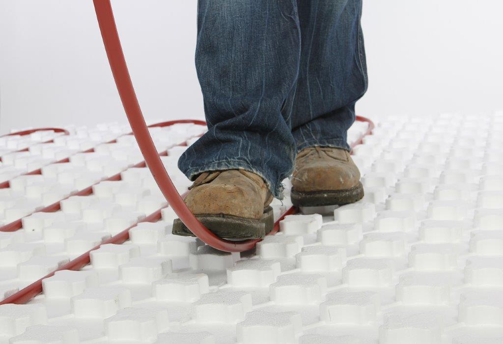 Worker installing pex piping into Heat Sheet radiant flooring system