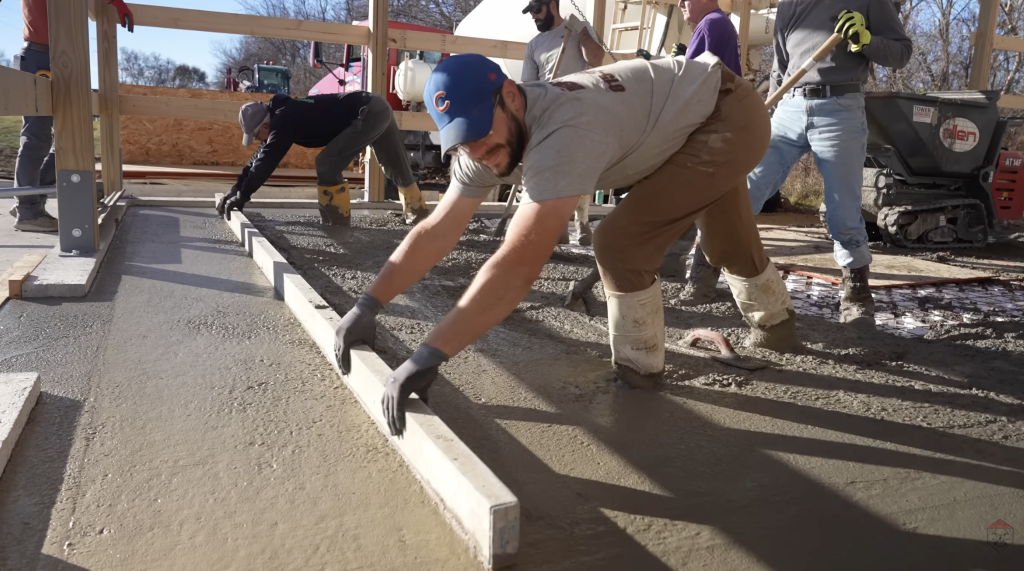 The crew screeds the concrete to establish a flat, consistent slab surface