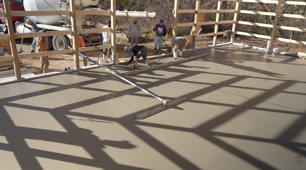 The crew bull floats the slab, smoothing the surface and bringing the concrete to a consistent level before finishing.