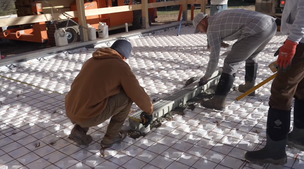 The crew installs and laser-sets the floor drain so the slab can be screeded precisely to the correct slope.
